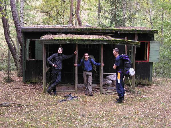 (Zprava) Tom, Maran a Kvtko pzuj ped polorozpadlou lesn chatou.